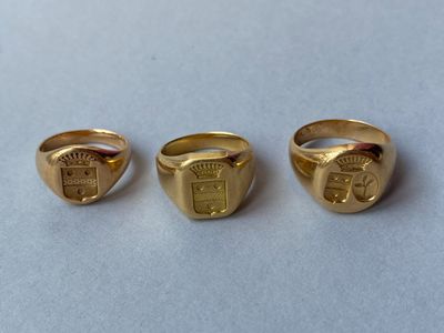 trois anneaux en or sur lesquels figurent un blason et un bouclier