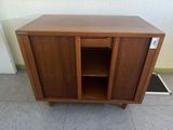 une photo d'une armoire en bois dont la porte est ouverte, posée à même le sol