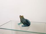 a small figurine of a frog sitting on top of a glass table