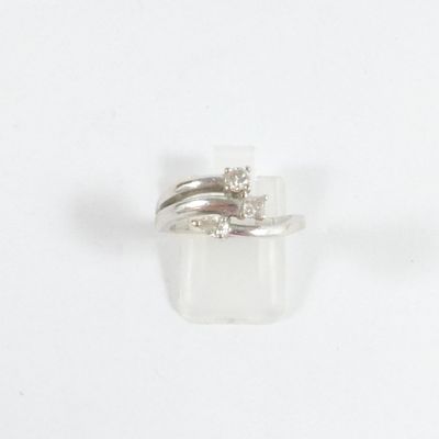 une bague sertie d'un diamant, posée sur une surface blanche