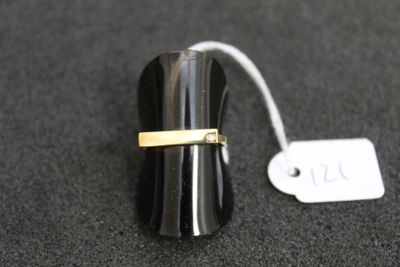 un anneau noir orné d'une bande dorée sur un fond noir