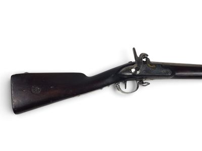 un vieux fusil exposé sur une surface blanche