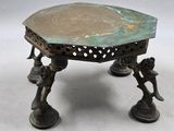 une petite table en bronze sur laquelle est posé un oiseau