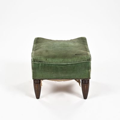 un repose-pieds rembourré avec une assise recouverte de velours vert