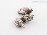 two small silver birds sitting on top of a white surface