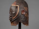 a wooden mask on a stand on a gray background