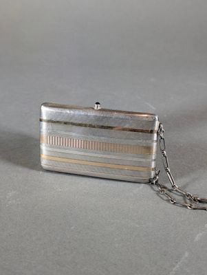 a silver purse with a chain around it on a table