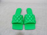 a pair of green plastic slippers sitting on top of a bed