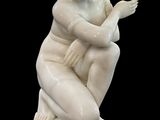 statue d'une femme assise sur un socle carré, les mains posées sur les genoux