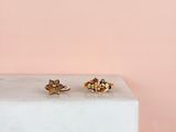 a pair of gold stud earrings sitting on top of a marble block