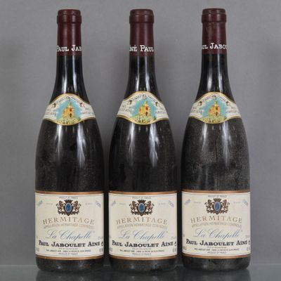 Trois bouteilles de vin sont alignées sur une table en verre