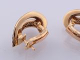 pair of yellow gold earrings with diamonds on them on a white surface