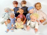 a lot of dolls that are sitting together on a white surface