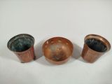 three copper vases sitting on top of a table next to each other