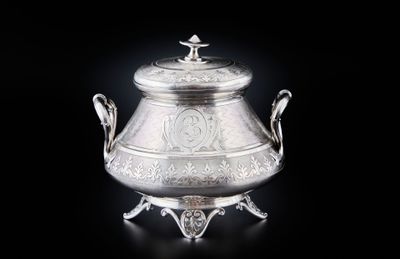 une théière ancienne en métal argenté sur socle, ornée de motifs élaborés