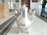 une théière en argent posée sur une table au milieu d'une pièce