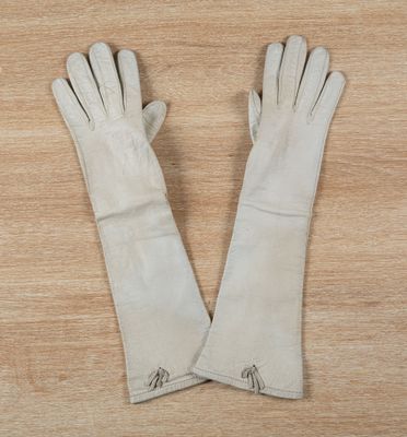 two pairs of white leather gloves on a wooden surface