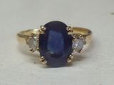 une photo d'une bague sertie d'un saphir bleu et de diamants, posée sur une surface blanche