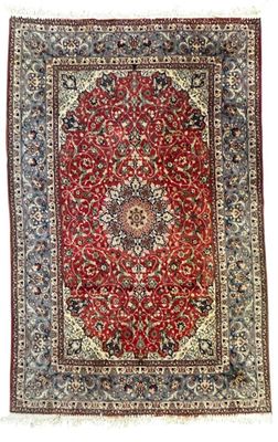 un tapis rouge et bleu orné d'un motif en médaillon sur fond blanc