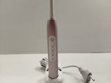 a pink electric toothbrush sitting on a white table