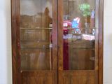 une armoire en bois avec une porte vitrée et une horloge posée dessus