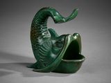 un gros plan sur une sculpture verte représentant un poisson la bouche ouverte