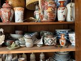 a wooden cabinet with many different types of pottery on it