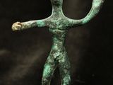an ancient bronze statue of a man holding a ball in his hand