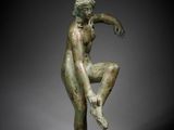 a bronze statue of a man sitting on his knees