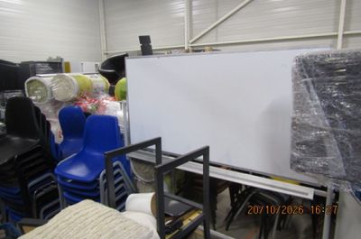 de nombreuses chaises et tables dans un entrepôt où se trouve un tableau blanc