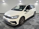 une Volkswagen Touran blanche garée dans une pièce au sol à carreaux