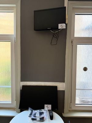 une petite table sur laquelle est posée une télécommande, devant deux fenêtres