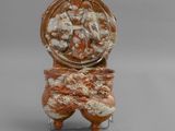 un vase orange et blanc posé sur un socle en métal