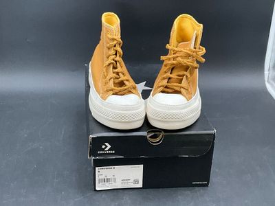 yellow converses are on a black box on a gray surface