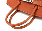 an orange leather handbag with a metal clasp on a white background