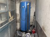un réservoir d'eau bleu posé dans un coin d'une pièce