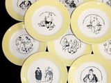 yellow and white plates with drawings of people on them on a black background