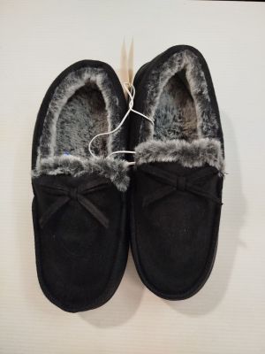 une paire de pantoufles noires doublées de fourrure, posées sur un fond blanc
