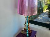 une lampe violette posée sur une table violette devant une fenêtre