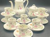 nine cups and saucers and a teapot on the table