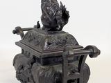 bronze statue of a man sitting on top of a box on a white surface