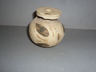 un petit vase muni d'un couvercle posé sur une table