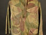 an old military jacket on a mannequin stand against a black background