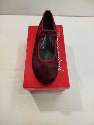 une boîte rouge sur laquelle est posée une paire de chaussures, posée sur une surface blanche