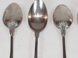 three silver spoons are lined up on a white surface