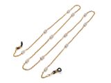 une chaîne en or ornée de perles et de perles noires sur fond blanc
