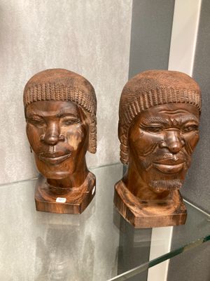 deux sculptures en bois représentant des têtes, exposées dans une vitrine
