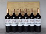 six bouteilles de vin rouge sont alignées devant une caisse en bois