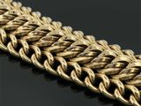 gros plan d'un bracelet en chaîne en or sur une surface noire