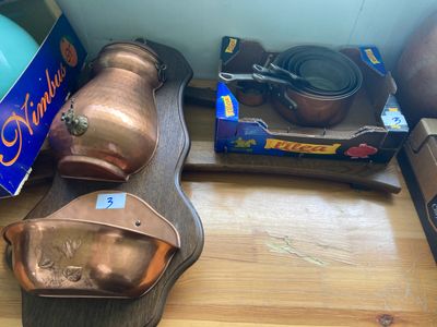 plusieurs casseroles et poêles en cuivre posées sur une table en bois